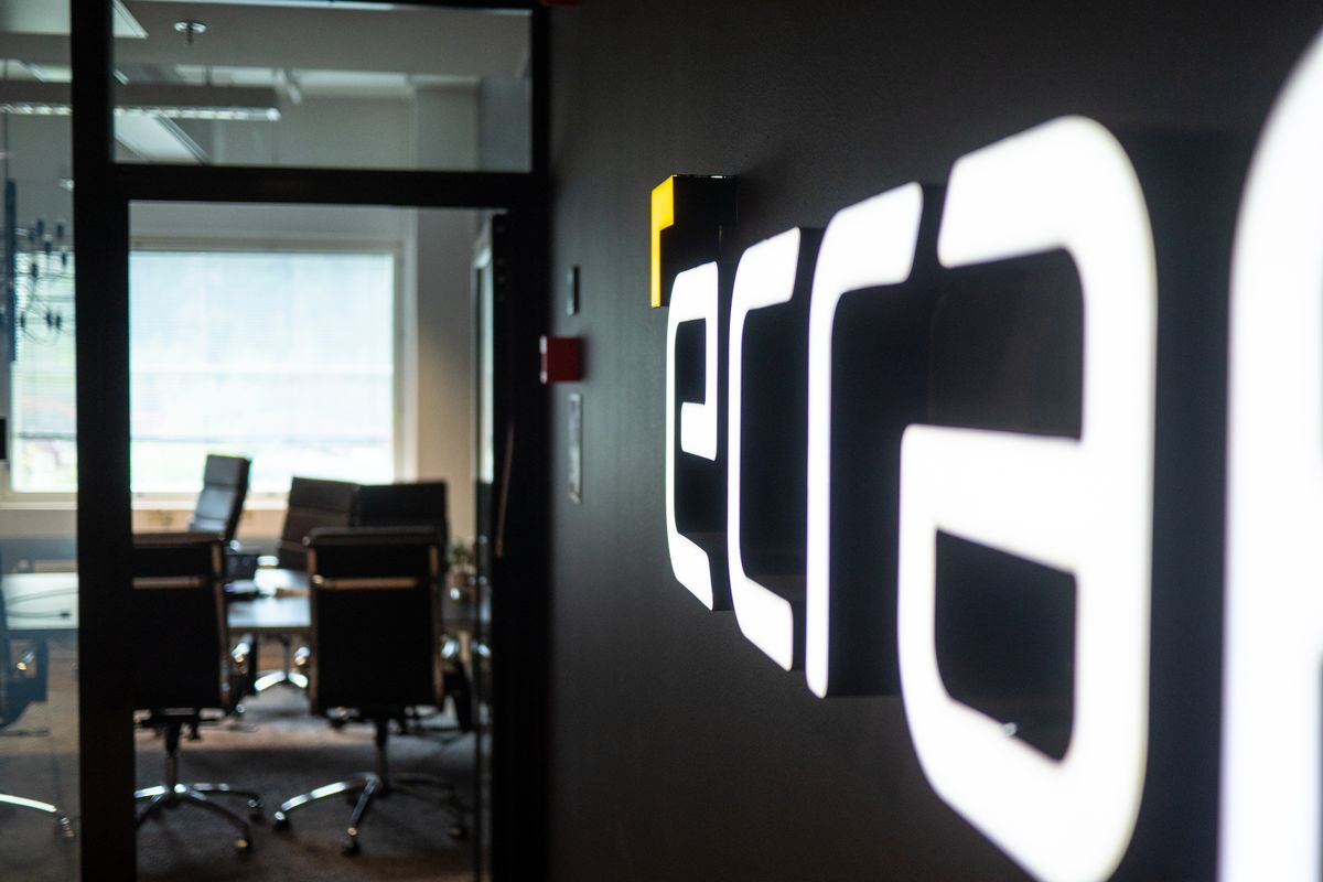 Backlit eCraft wordmark sign at the office entrance, meeting room visible through a doorway